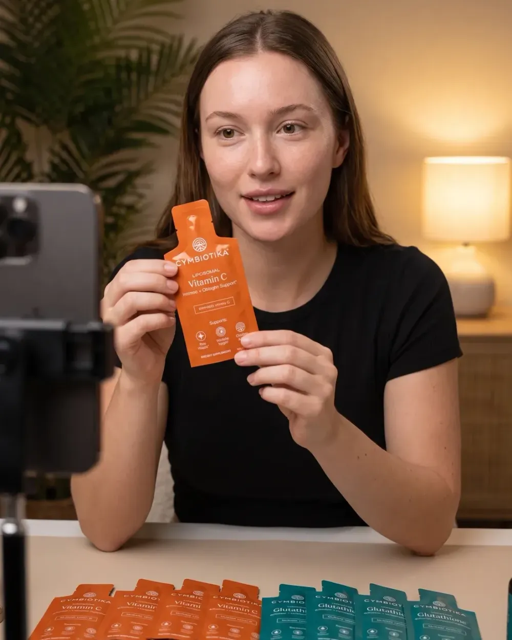 Host presenting Cymbiotika Liposomal Vitamin C to a phone camera on a live stream